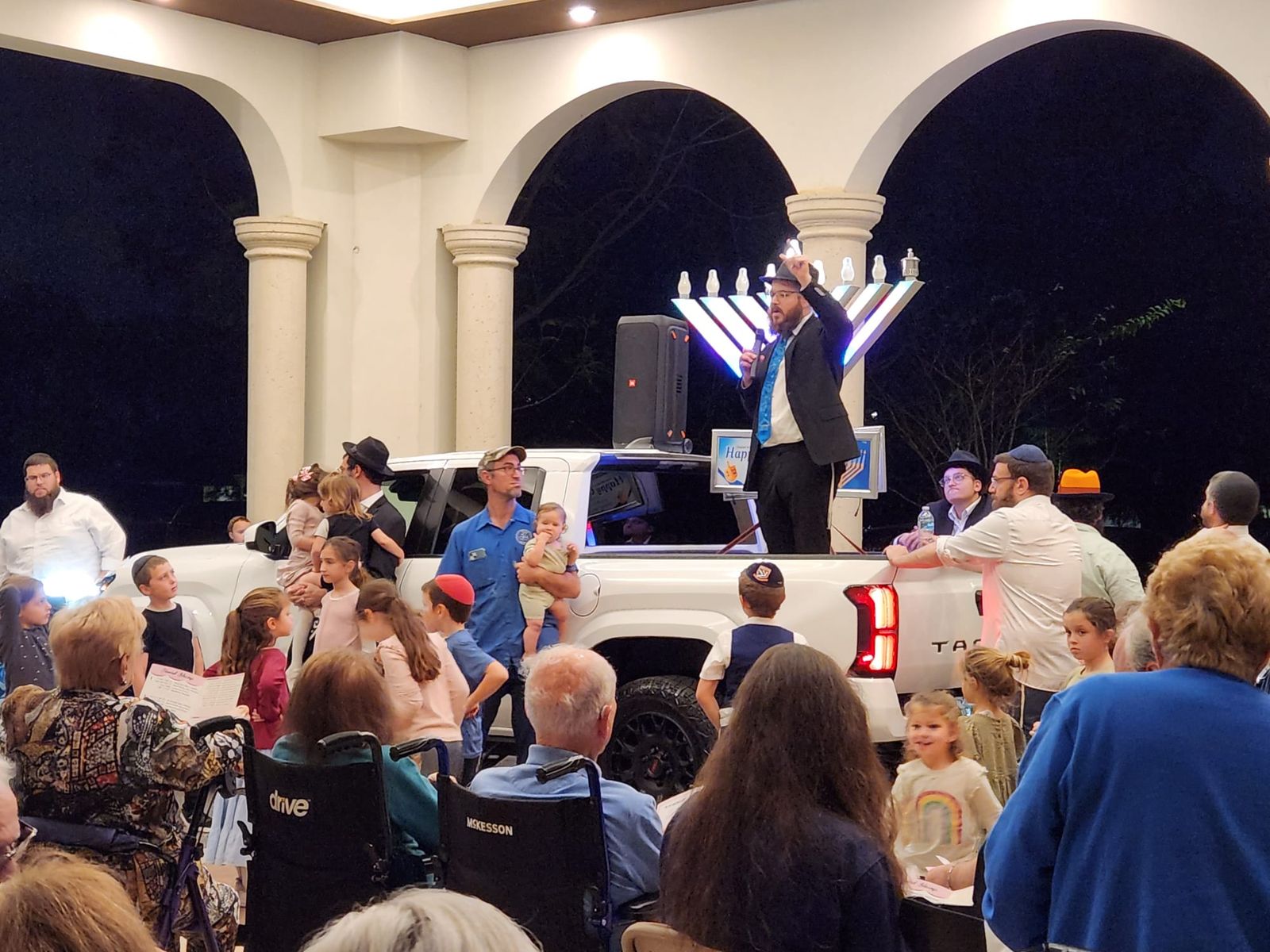 Rabbi Moshe Wolvovsky of The Wisdom Circle of Boca Raton leads a menorah lighting for senior residents at night